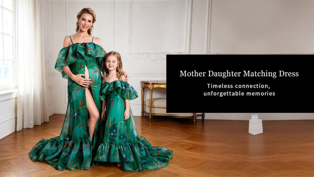 A woman and a young girl posing together in matching green gowns, standing in front of a white wall with a black sign.