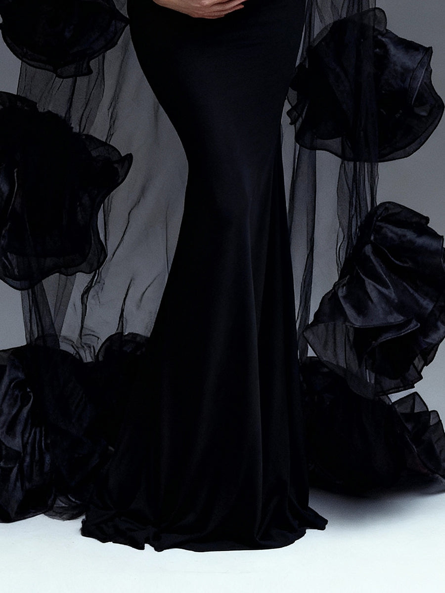 Black evening gown with large black floral accessories on a gray background