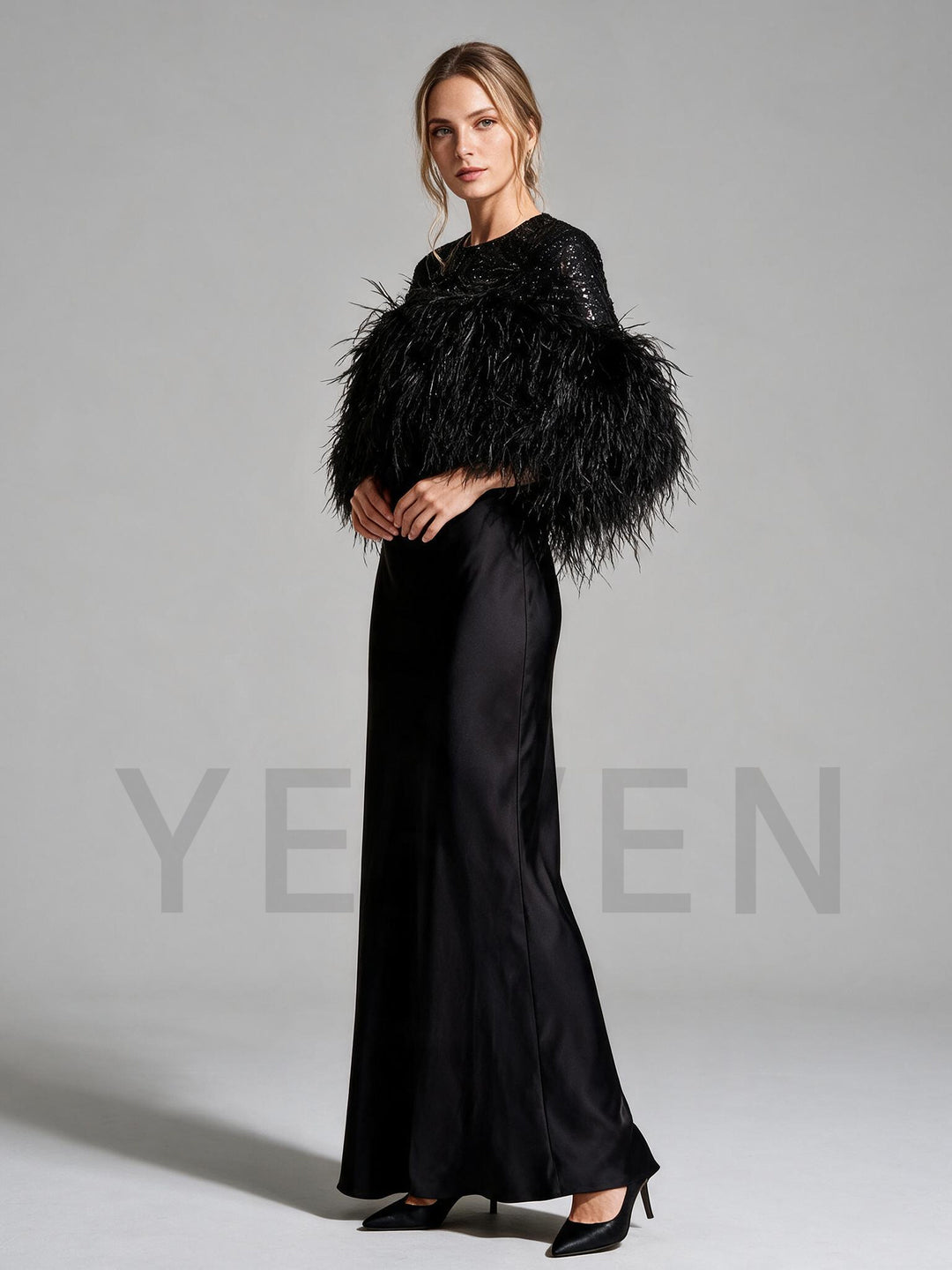 Side profile of a black satin maxi evening gown with feather trim bodice.