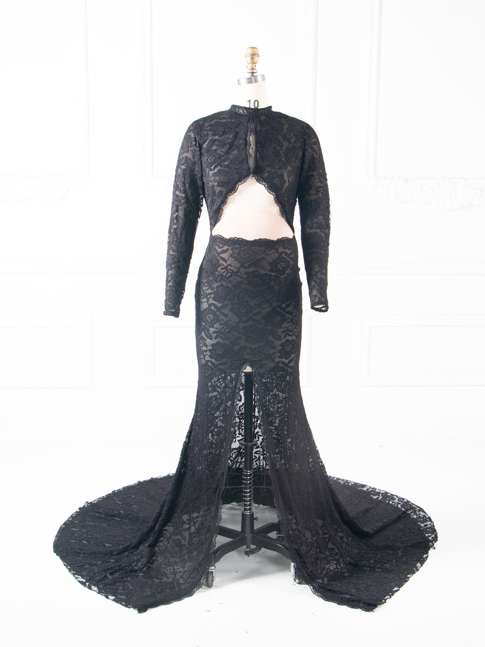 Full-length view of a black two-piece lace maternity mermaid gown, featuring a long-sleeve open-back crop top and a sweeping lace mermaid train, displayed on a mannequin.