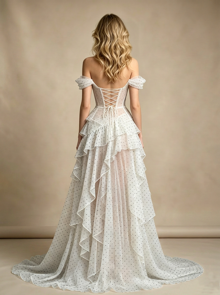 Back view of a model wearing a boho fairycore evening gown with a lace-up corset back and layered ruffle skirt.