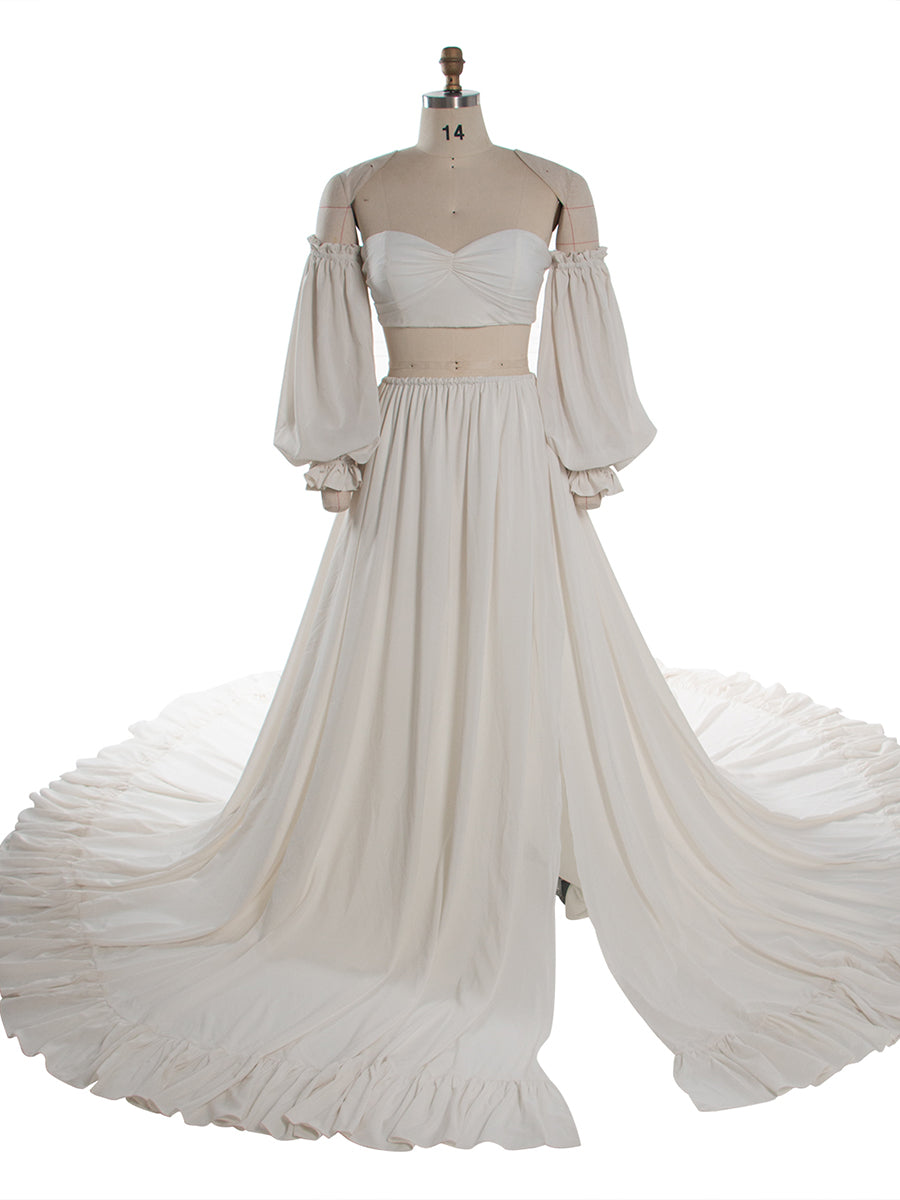 An off-the-shoulder two-piece costume set displayed on a mannequin, featuring a strapless sweetheart crop top with long puff sleeves and a matching high-waisted, flowing maxi skirt with a ruffled hem.