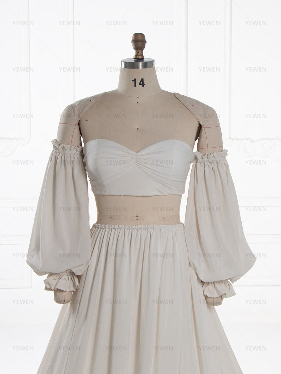 A cream-colored two-piece costume or dress displayed on a beige mannequin. The set features a strapless sweetheart bustier top with gathered detailing at the bust and a matching long, voluminous puff skirt.