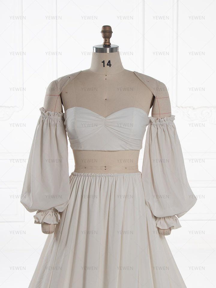 A cream-colored two-piece costume or dress displayed on a beige mannequin. The set features a strapless sweetheart bustier top with gathered detailing at the bust and a matching long, voluminous puff skirt.