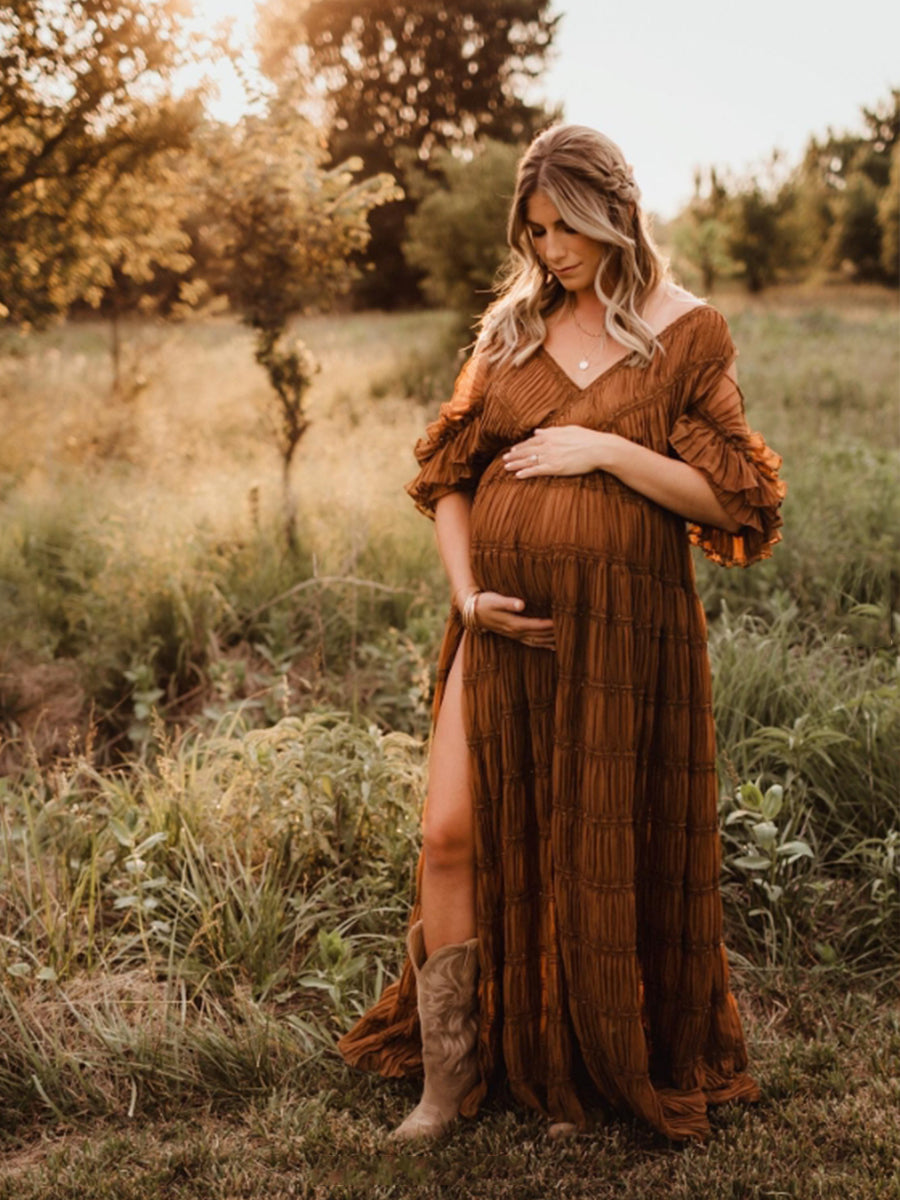 Woman in a brown dress standing in a field with sunset lighting