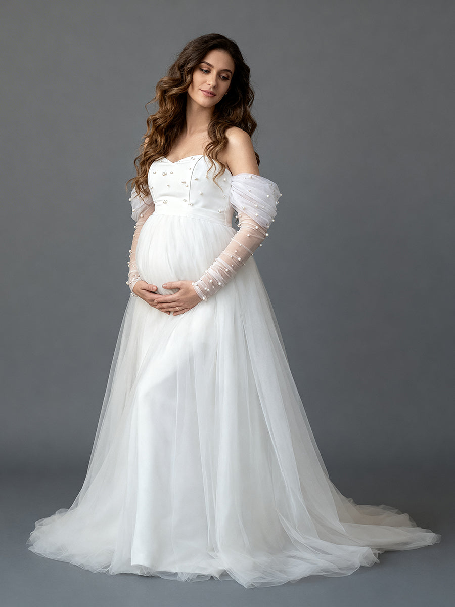 Full front view of a pregnant model wearing a custom maternity wedding dress with pearl long sleeves and tulle skirt.