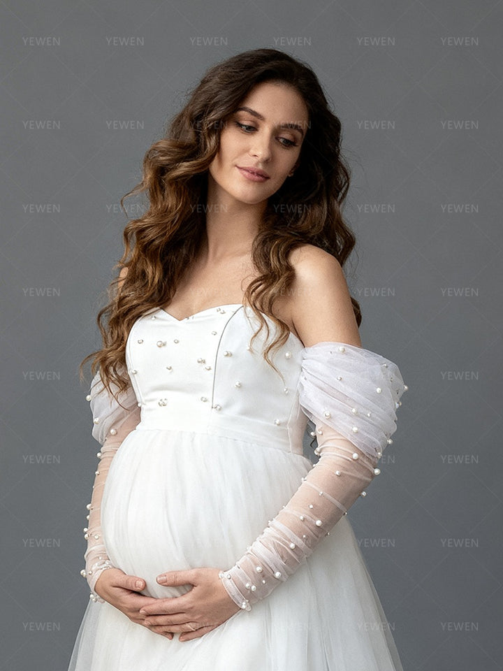 Close-up side view of a pregnant model wearing a custom maternity wedding dress highlighting the pearl sleeves.