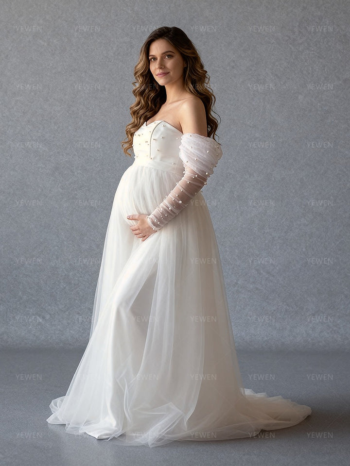 Side view of a pregnant model wearing a custom maternity wedding dress with pearl sleeves and tulle skirt.