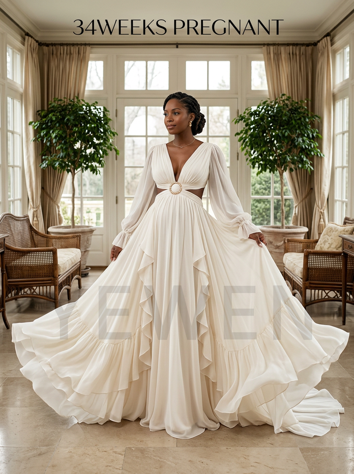 A pregnant model wearing a long-sleeve, deep V-neck, tiered A-line wedding gown in cream/off-white, standing in a bright, elegant room with large windows, curtains, and potted plants. Text overlays read '34WEEKS PREGNANT' at the top and a large semi-transparent 'EME' watermark across the center.
