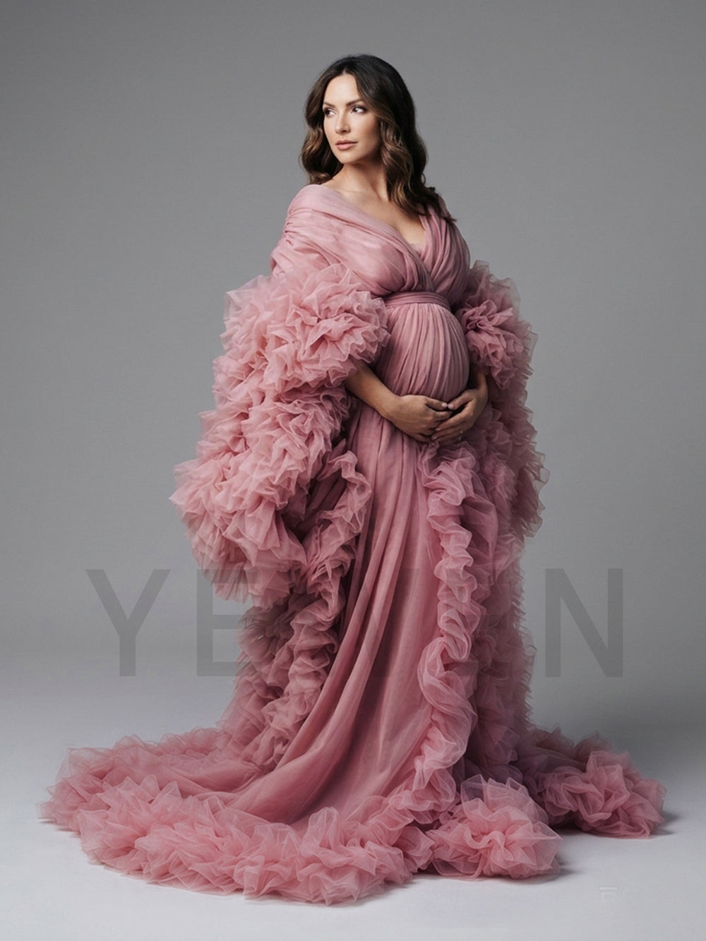 Side profile of a dusty pink tulle maternity gown with ruffle sleeves and a flowing skirt.