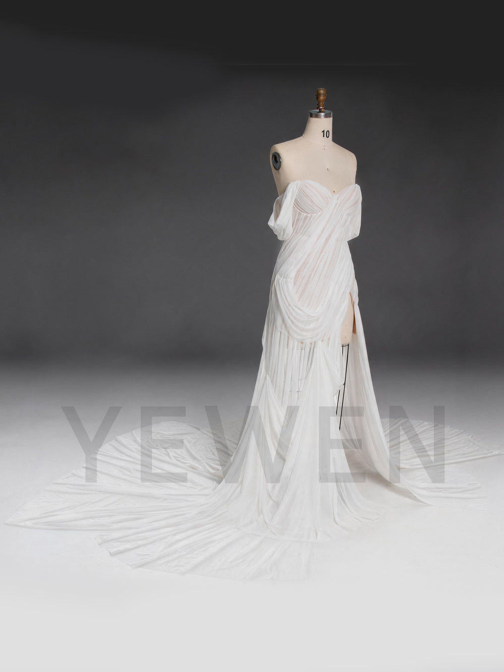 Side profile of a white chiffon bridal gown with a corset bodice and draped neckline.