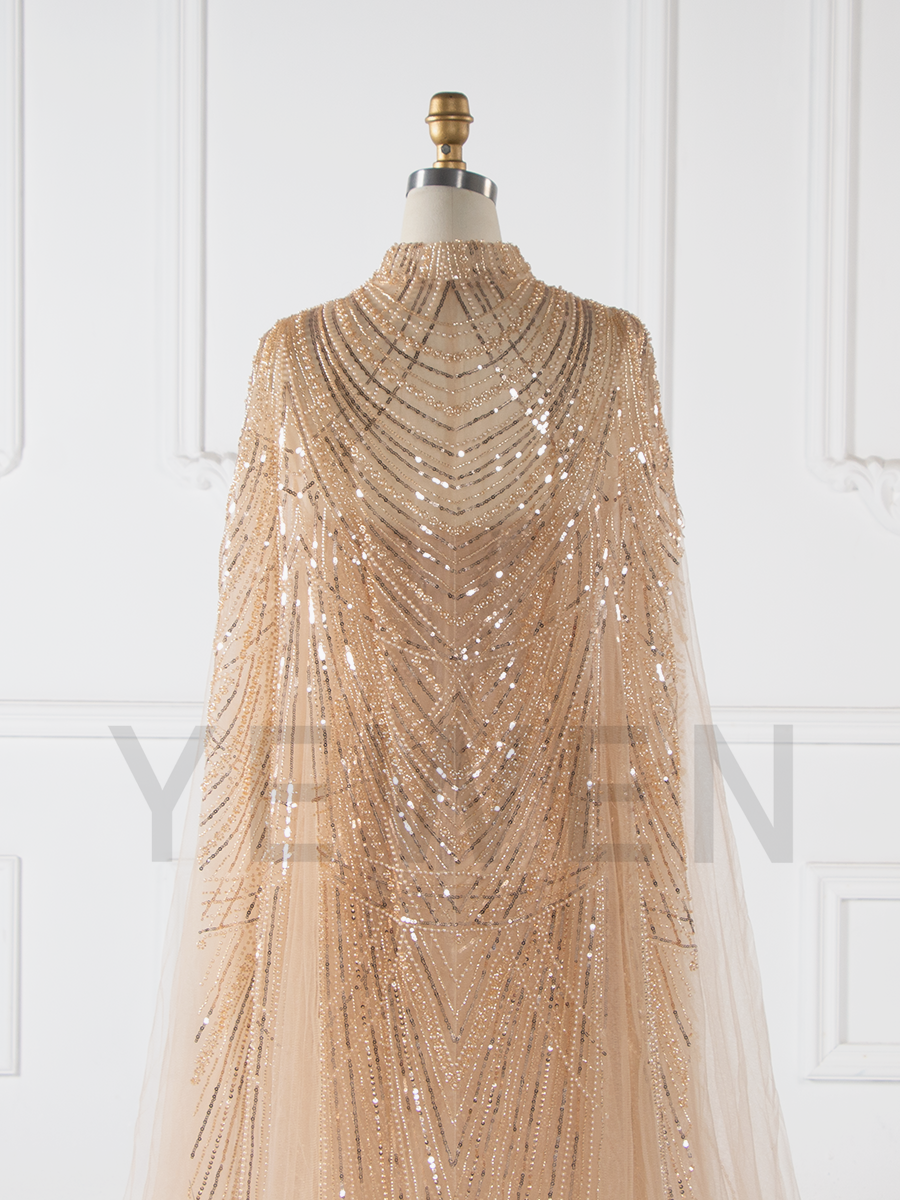 Close-up of hand-beaded detailing on evening dress with cape showing luxury craftsmanship and texture