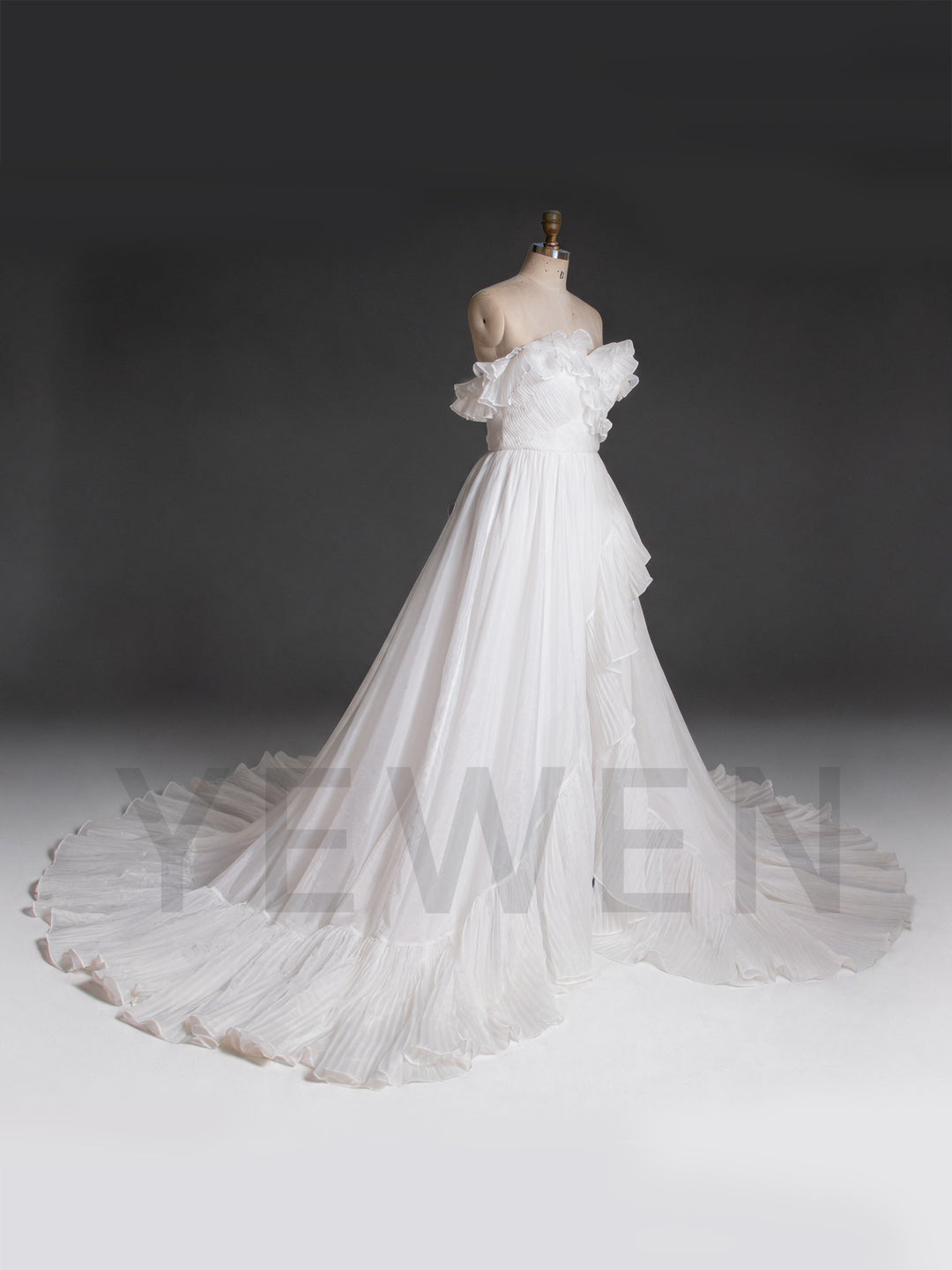 Side profile of a white organza pleated wedding dress with an off-shoulder neckline.