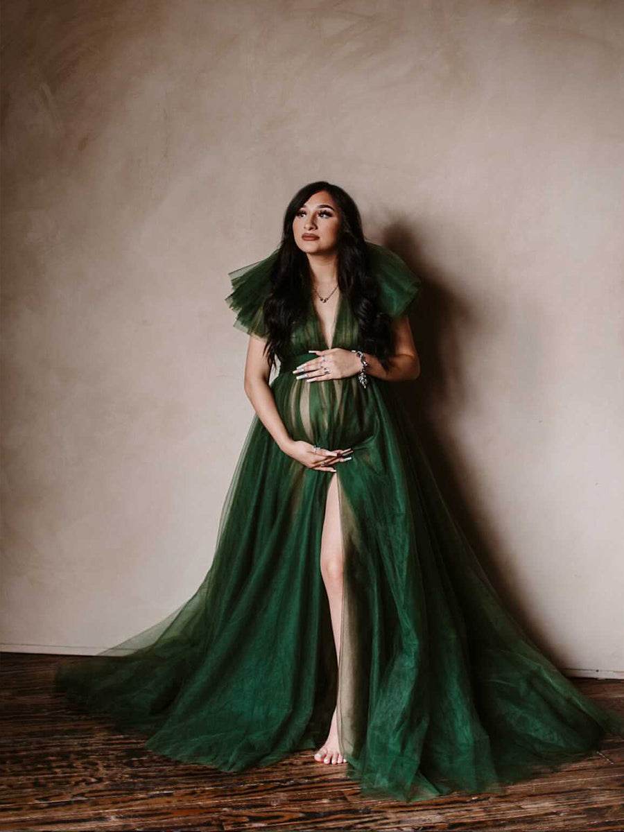 Front view of green maternity dress for photo shoot featuring tulle flowers and elegant flowing maxi design
