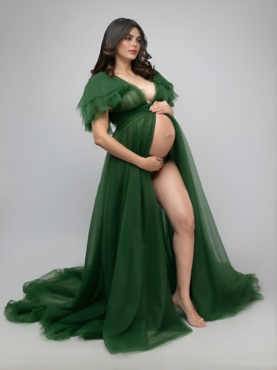 Front view of green maternity dress for photo shoot featuring tulle flowers and elegant flowing maxi design