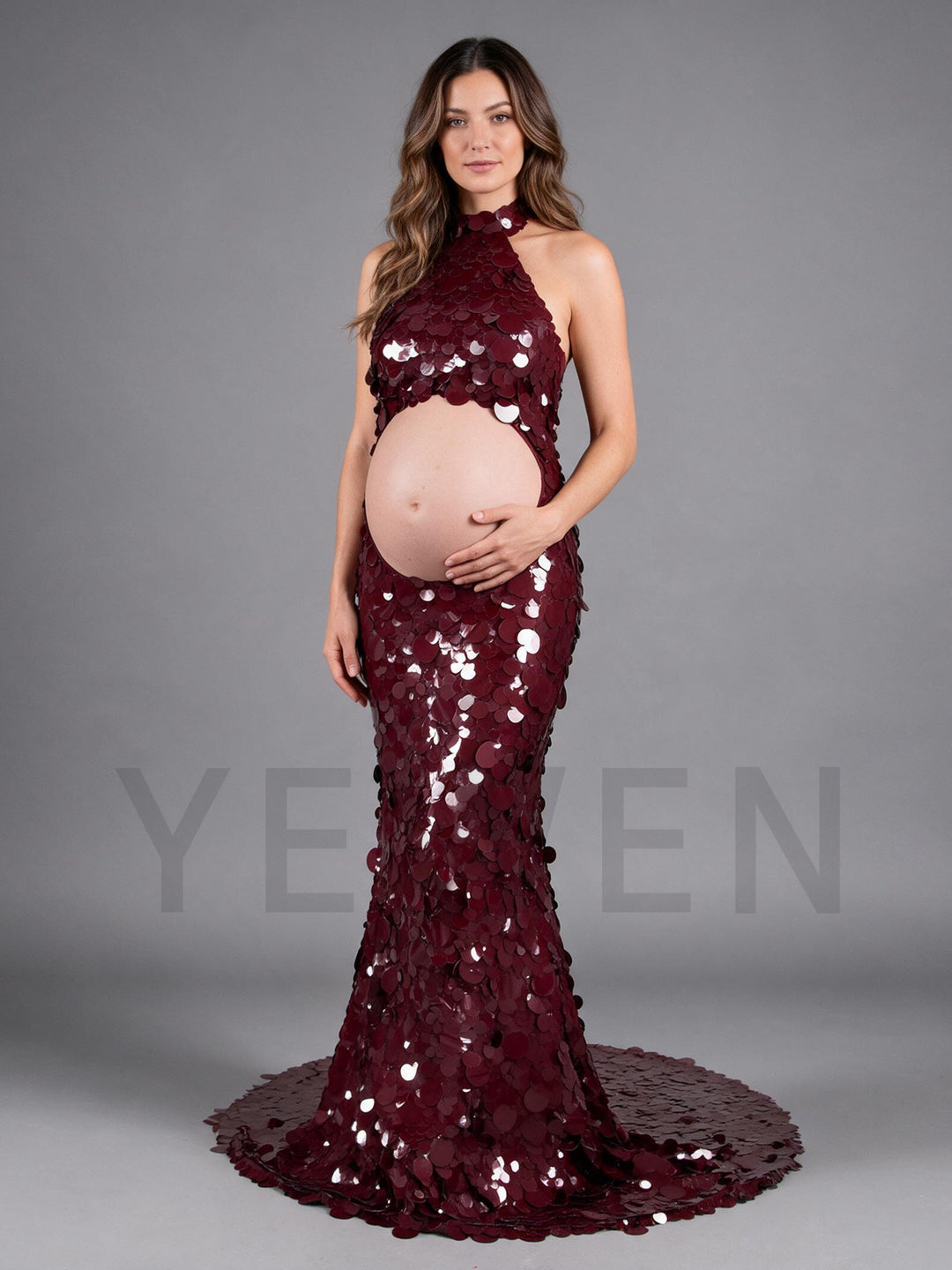 Side view of a burgundy sequin maternity gown with a cutout belly and halter neck.