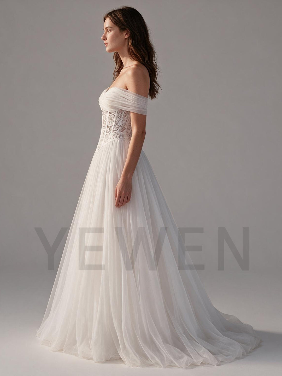 Side profile of an ivory off-shoulder wedding dress with a flowing tulle skirt.