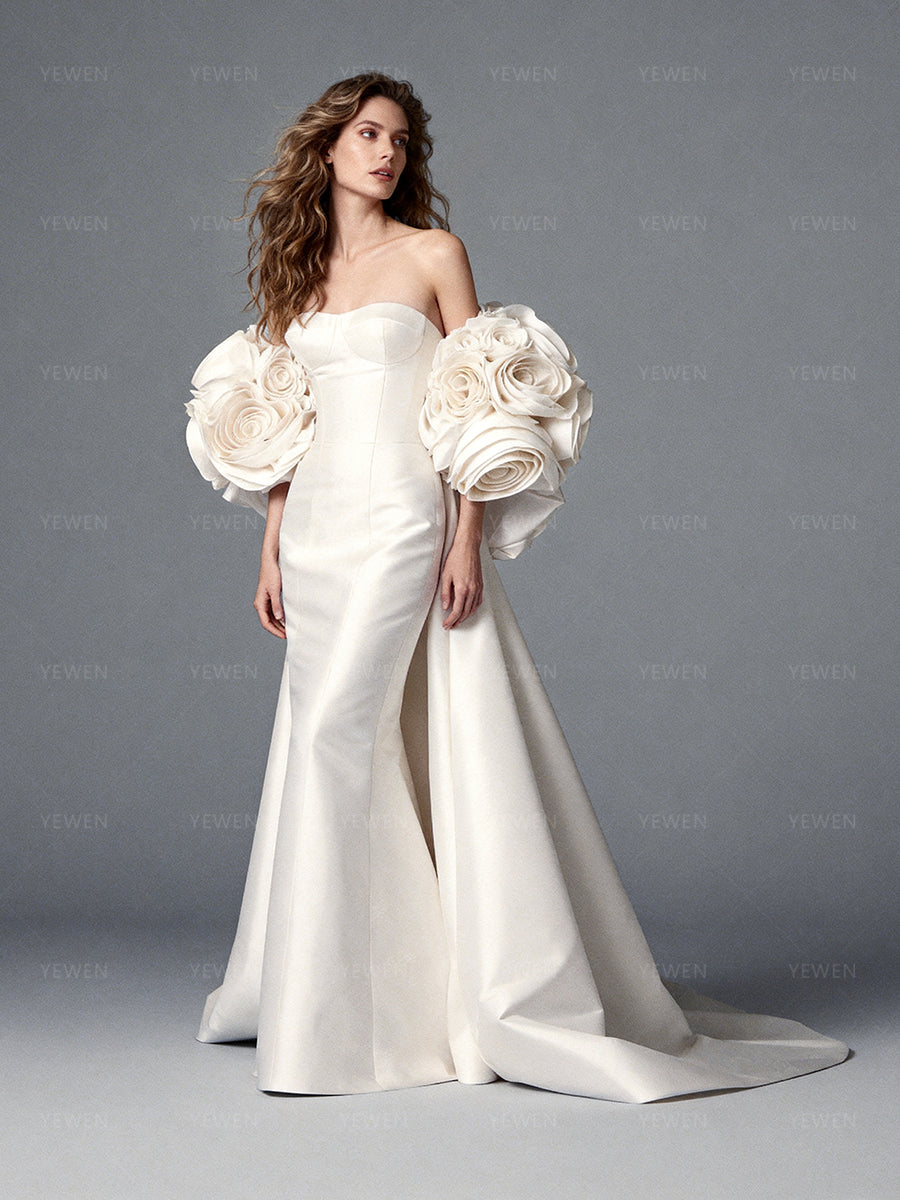 Side view of a model wearing an ivory satin off-shoulder mermaid wedding dress with a 3D floral cape.