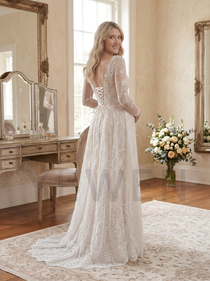 A woman wearing a long-sleeve lace wedding gown with a lace-up open back, standing in a softly lit bridal room with mirrors, a vanity, and floral arrangements.