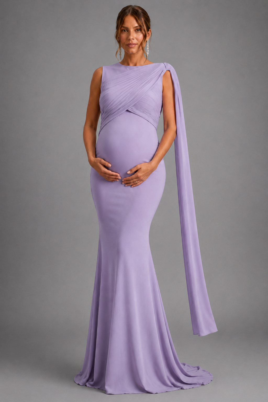 A pregnant model wearing a lavender purple maternity gown with a draped one-shoulder design and a long flowing train, standing against a solid gray studio background.