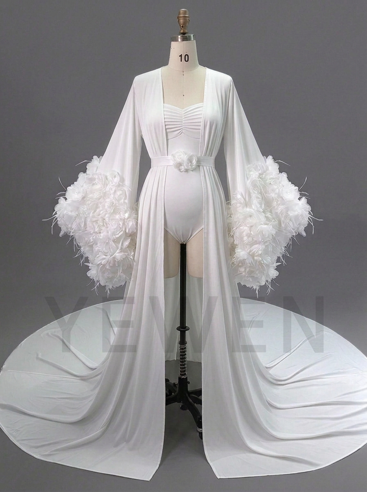 A white long-sleeve bridal gown displayed on a mannequin against a gray studio background. The dress features a sweetheart neckline, a gathered bodice, a long flowing train, and dramatic feathered sleeves.