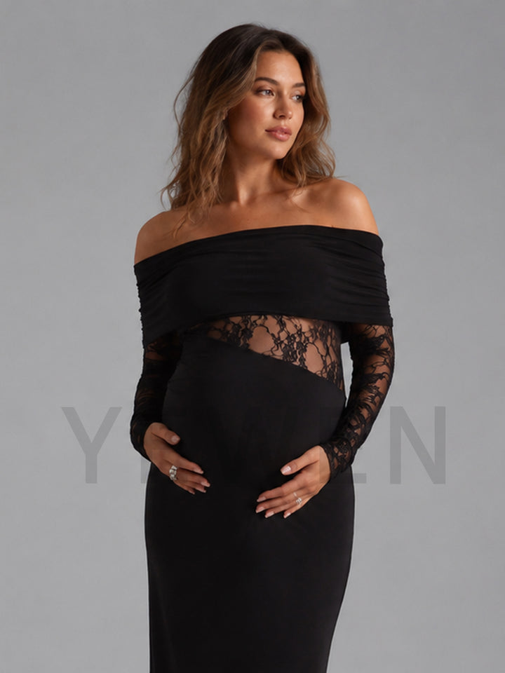 A pregnant model wearing a black off-the-shoulder maternity gown with long sheer lace sleeves and a lace waist panel, posed against a solid gray studio background.