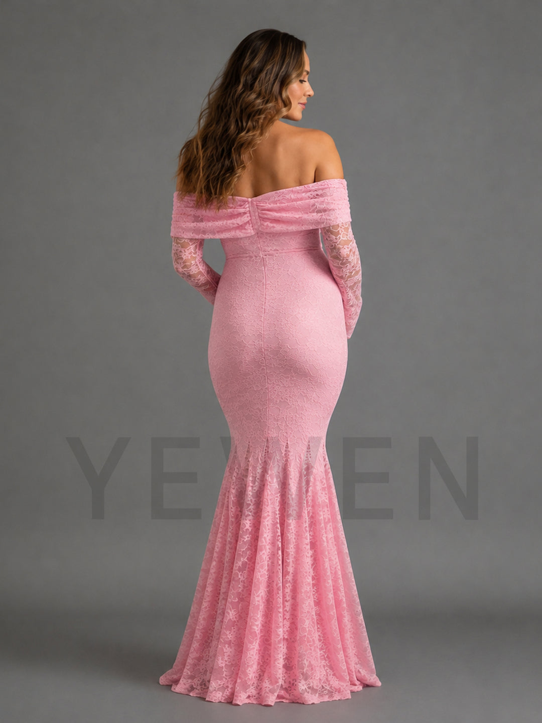 A woman modeling a pink off-the-shoulder mermaid gown with long lace sleeves, shown from the back against a solid gray studio background.