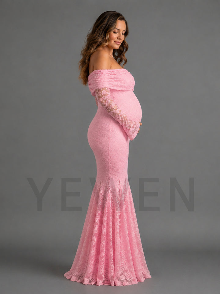 A pregnant model wearing a pink off-the-shoulder maternity gown with long lace sleeves and a flared lace hem, photographed against a plain gray studio background.