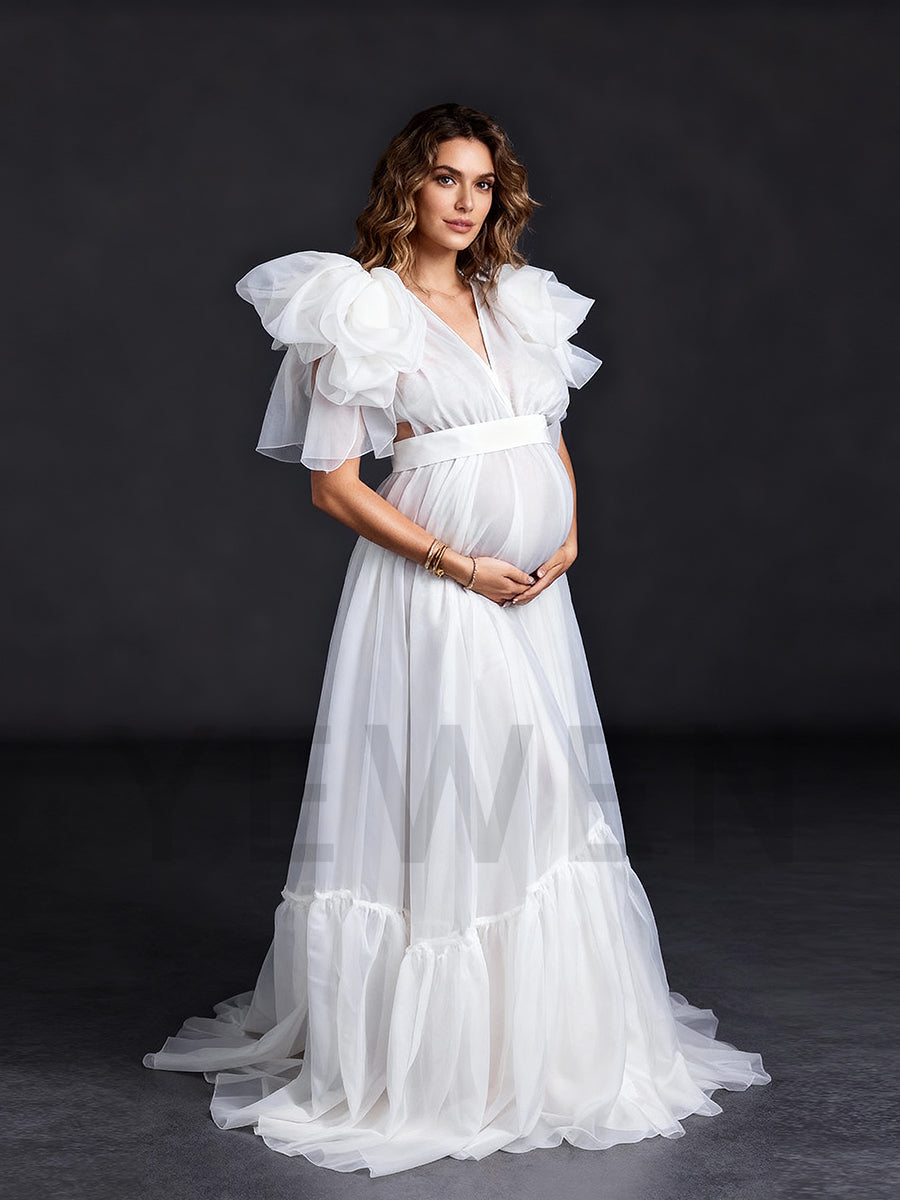 Side view of a pregnant model wearing a maternity wedding dress with an A-line silhouette and sheer organza fabric.