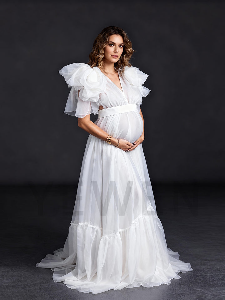 Side view of a pregnant model wearing a maternity wedding dress with an A-line silhouette and sheer organza fabric.