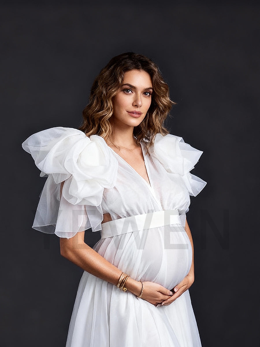 Close-up side view of a pregnant model wearing a maternity wedding dress highlighting the shoulder flower details and ruffle hem.