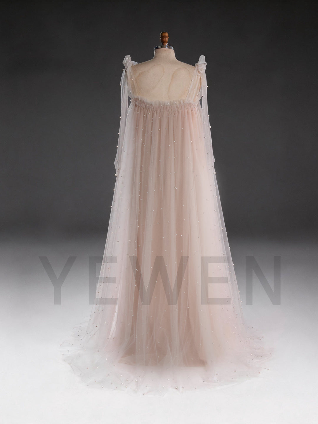 Back view of a blush pink sheer cape tulle dress for women, showing the flowing silhouette.