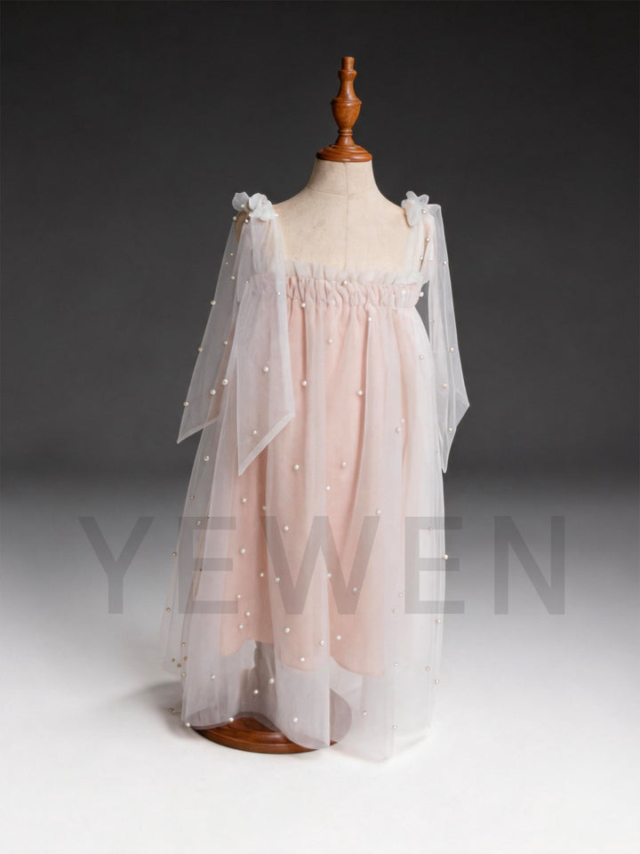 Back view of a blush pink sheer tulle dress for girls, showing the flowing cape.