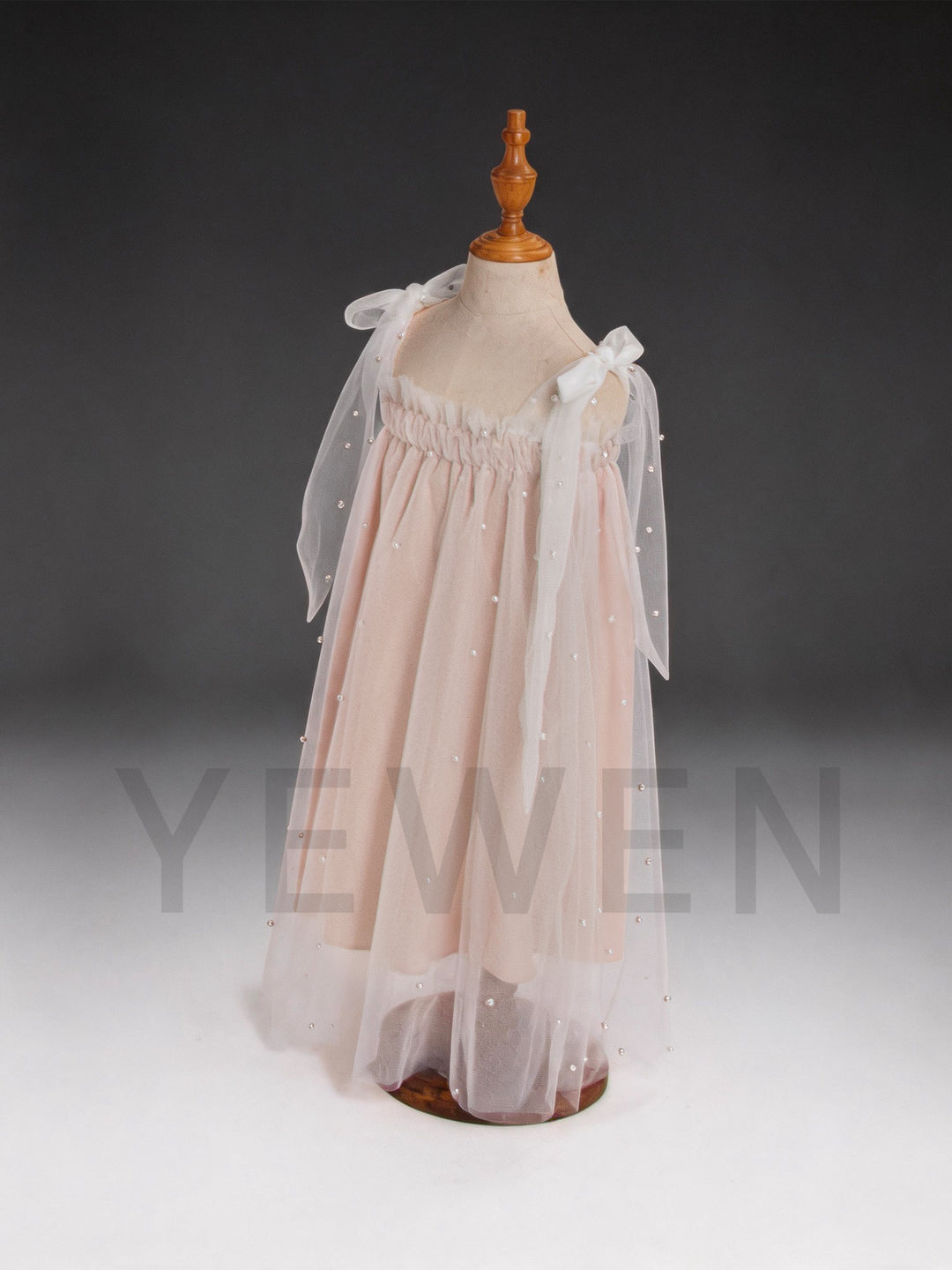 Side view of a blush pink sheer cape tulle dress for kids with pearl details.