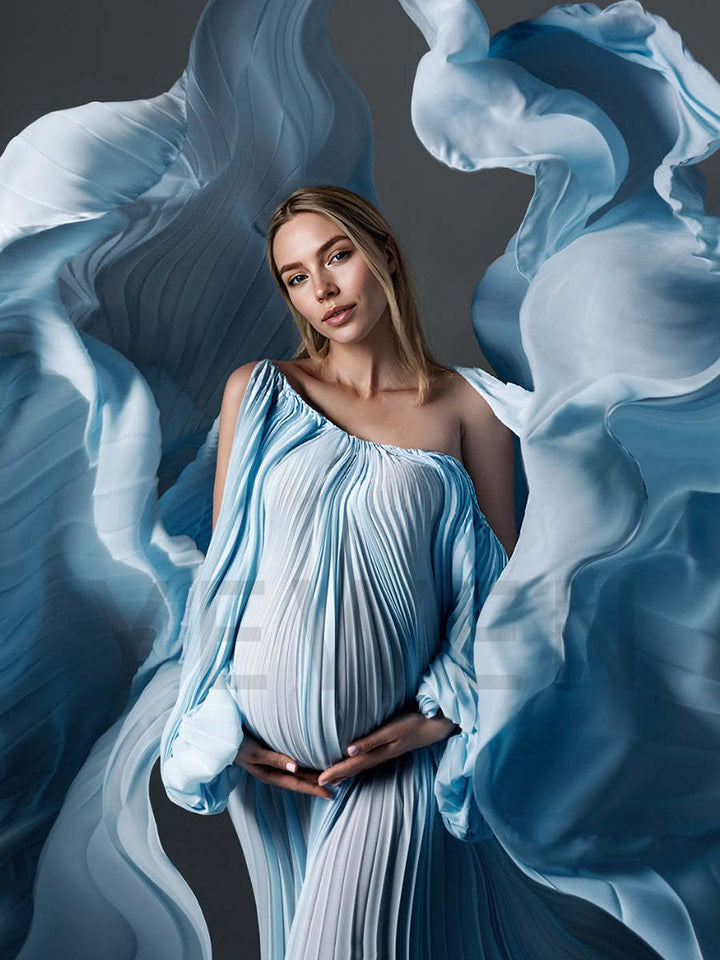 Woman in a flowing blue dress surrounded by blue fabric against a dark background