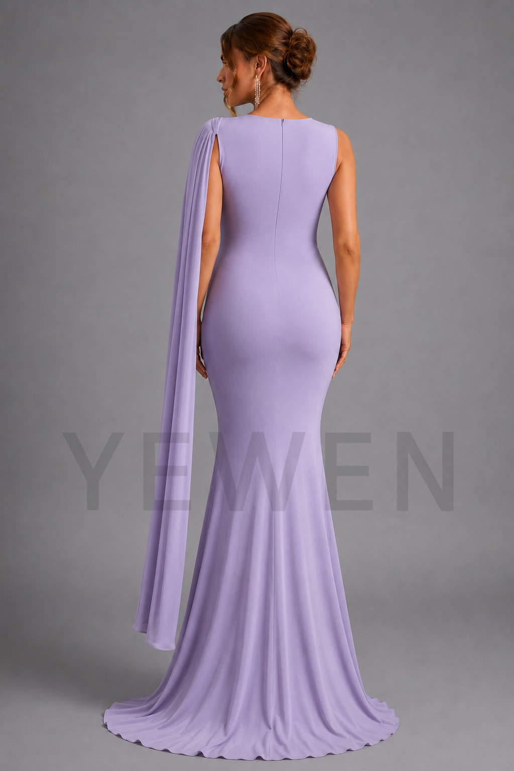 A woman modeling a lavender purple floor-length evening gown from the back, featuring a draped cape-style shoulder drape and a slight train, against a solid gray studio background.