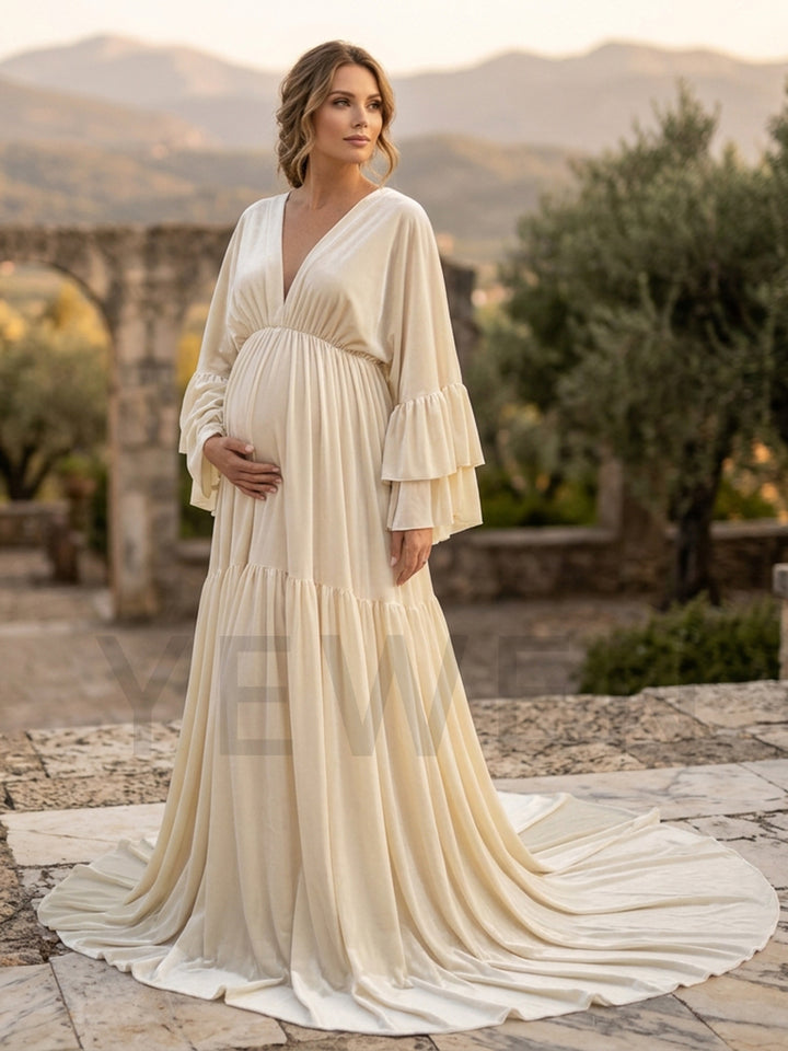 Pregnant woman wearing a cream velvet maternity photoshoot dress in an outdoor garden setting.