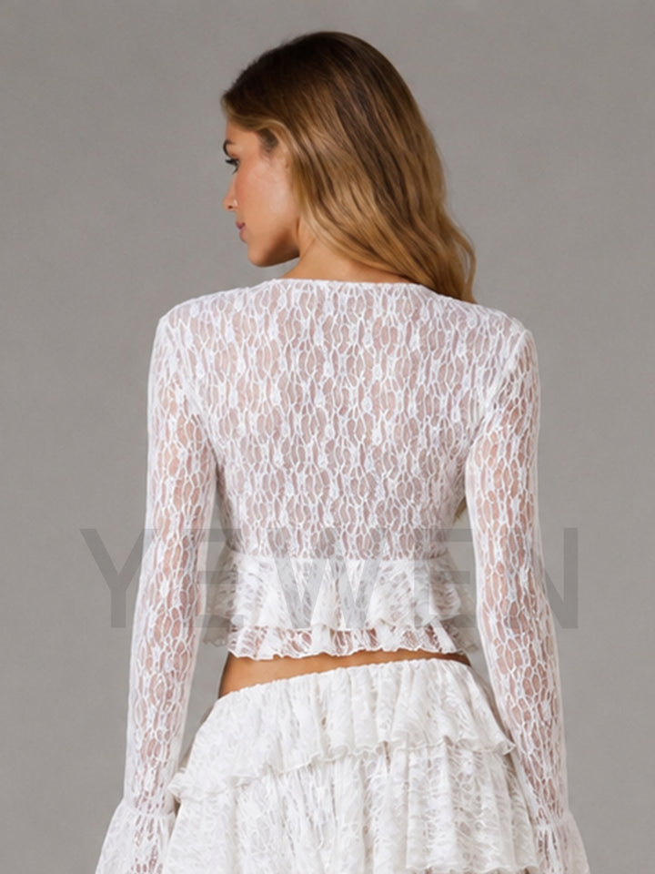 A woman shown from the back wearing a white lace long-sleeve crop top with a ruffled hem and a matching white ruffled skirt, against a plain gray studio background.