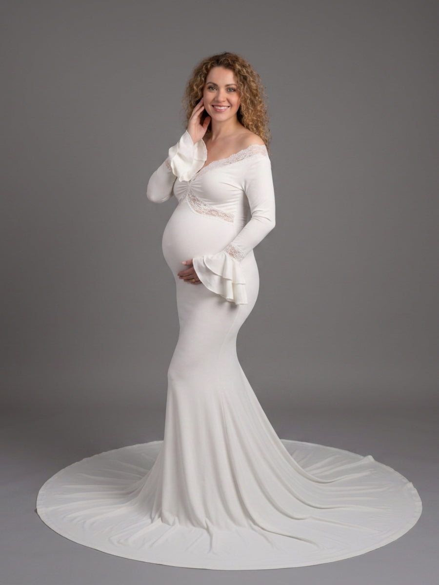 Full front view of a pregnant model wearing a white maternity photoshoot gown with a V-neckline and flared long sleeves.