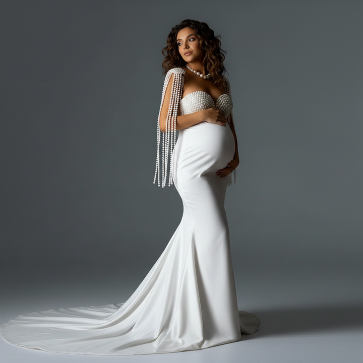 Side view of a pregnant model wearing a stunning white pearls mermaid maternity photoshoot gown with a sweeping train.
