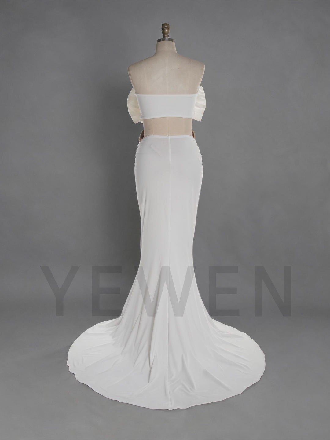 White two-piece gown displayed on a mannequin against a gray studio background. The set includes an off-the-shoulder strapless crop top with puff sleeves and a matching fitted mermaid-style skirt with a slight train.
