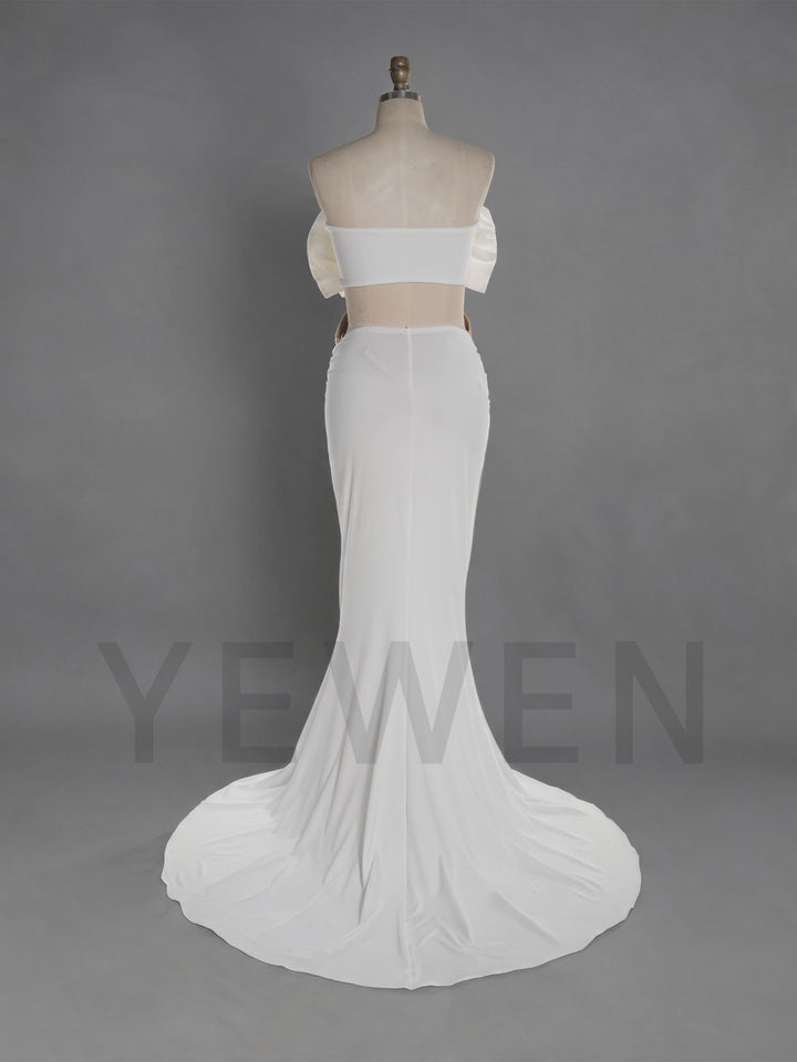White two-piece gown displayed on a mannequin against a gray studio background. The set includes an off-the-shoulder strapless crop top with puff sleeves and a matching fitted mermaid-style skirt with a slight train.
