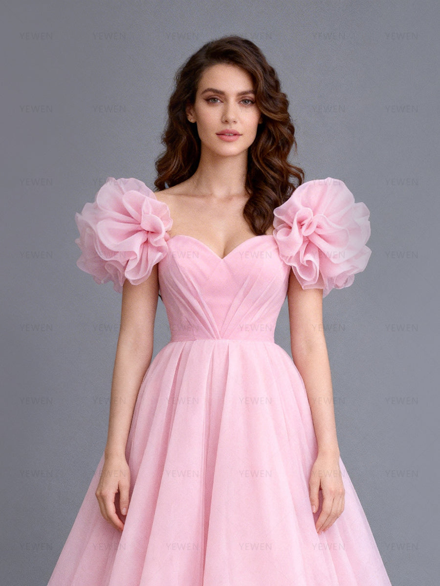 Close-up front view of a model wearing a blush tulle evening dress highlighting the sweetheart neckline and layered puff sleeves.