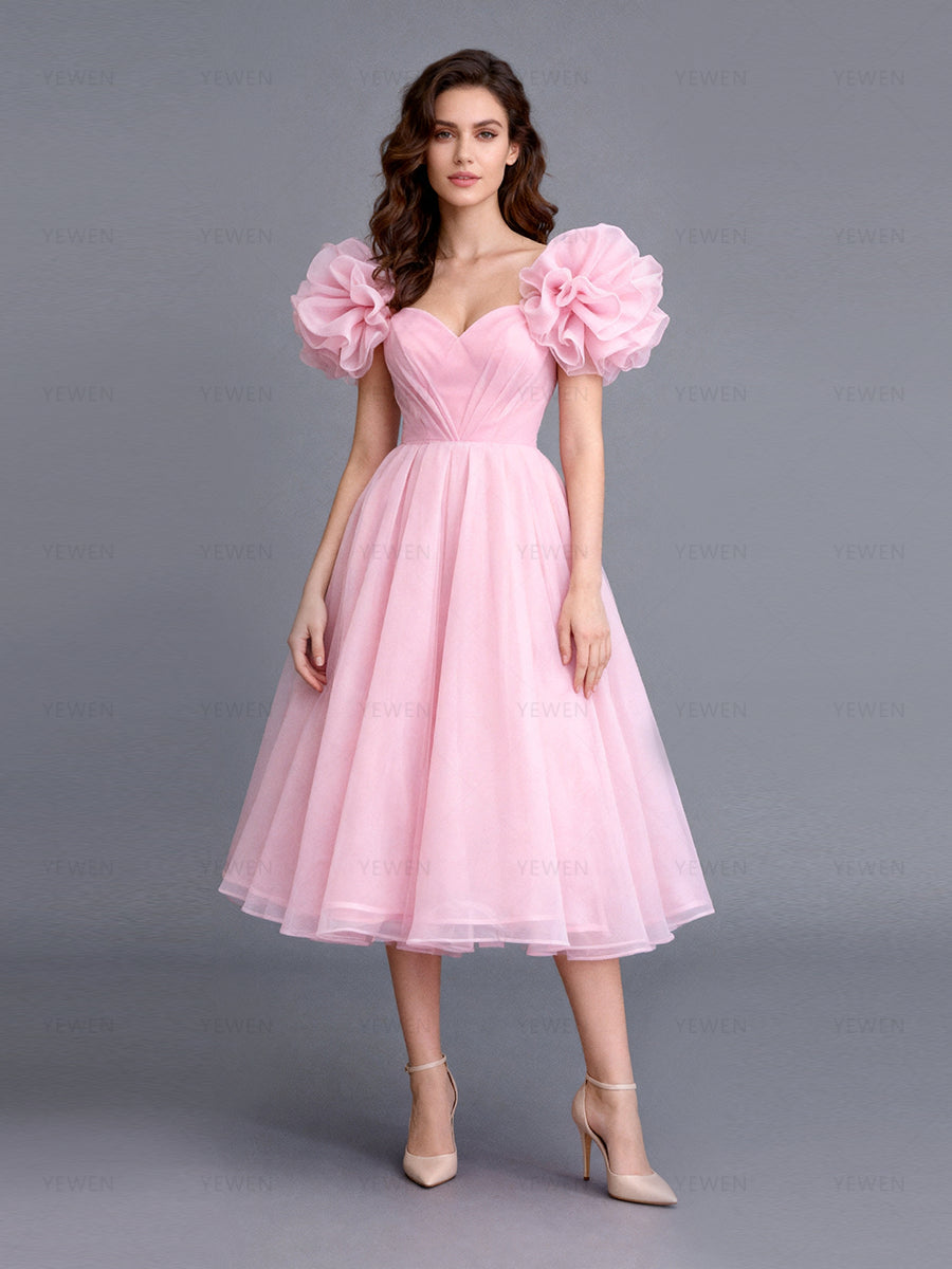 Front view of a model wearing a blush tulle A-line evening dress showing the voluminous puffed sleeves and flared skirt.