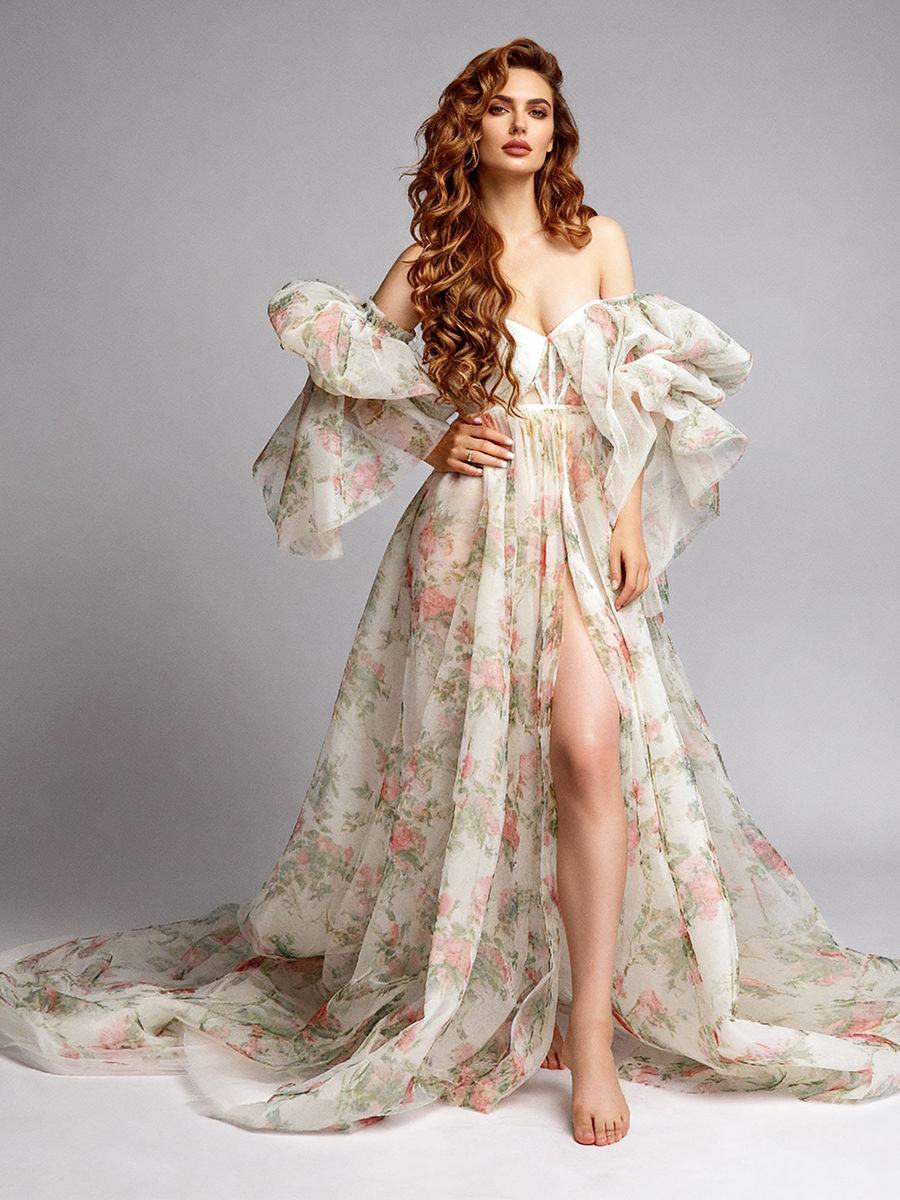 Full-body front view of a white floral off-shoulder maternity photoshoot gown with voluminous puff sleeves, a deep V-neckline, and a high side slit, displayed in a studio.