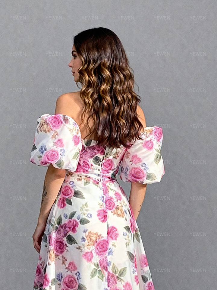 Close-up back view of a model wearing a floral organza elegant outdoor photoshoot dress highlighting the off-shoulder puff sleeves and fitted bodice.
