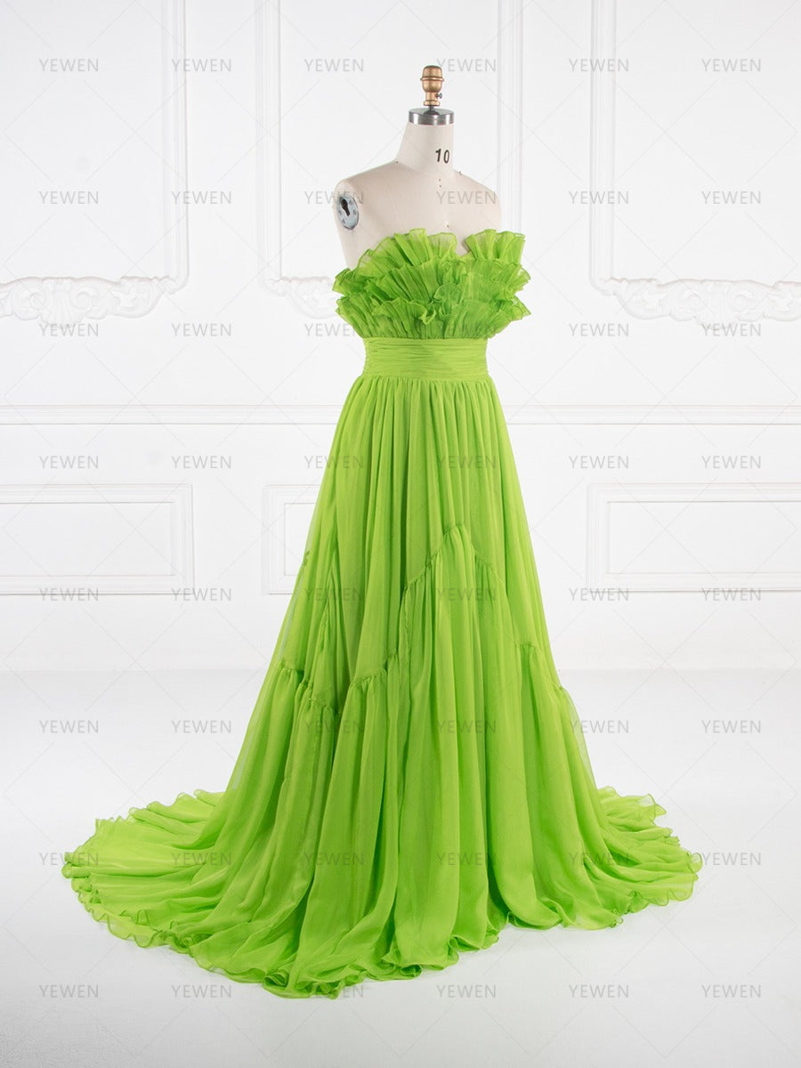Side view of a lime green ruffle evening gown showing the layered ruffle bodice and sweeping pleated skirt on a mannequin.
