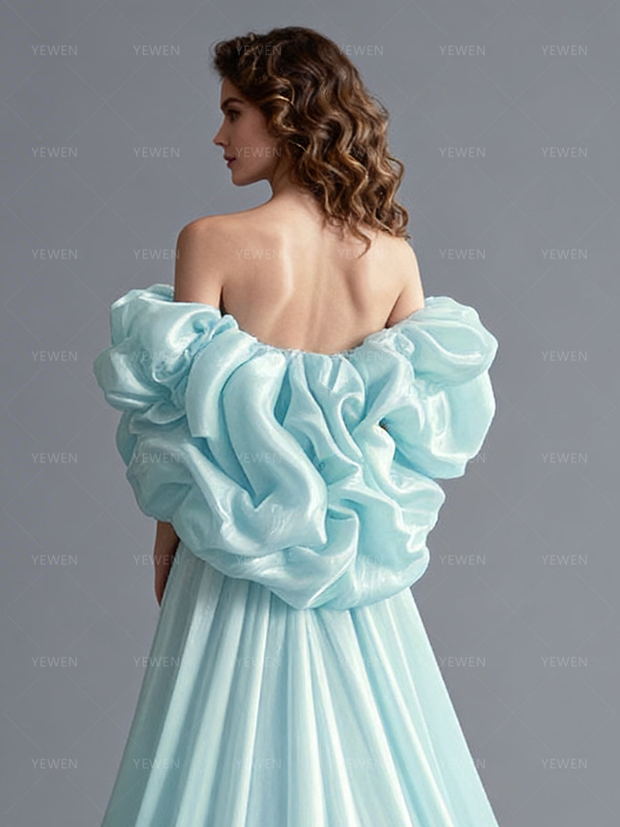 Close-up back view of a model wearing an ice blue flower cape bridal accessory with dramatic ruffled layers.