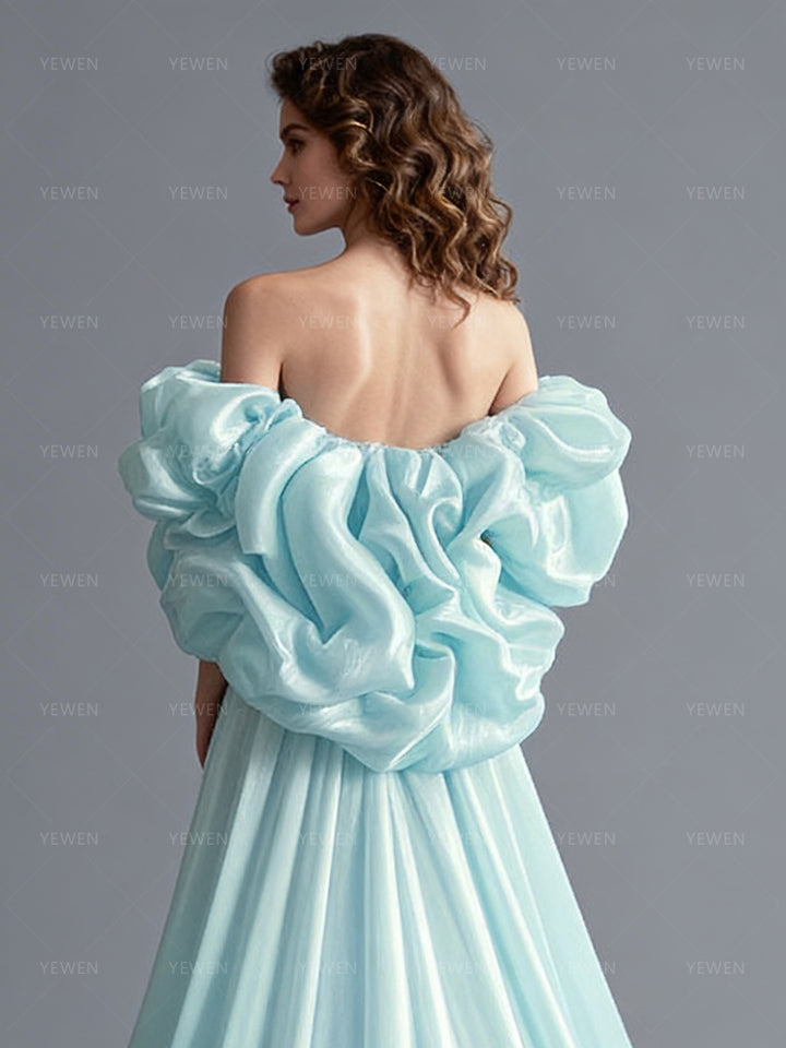 Close-up back view of a model wearing an ice blue flower cape bridal accessory with dramatic ruffled layers.
