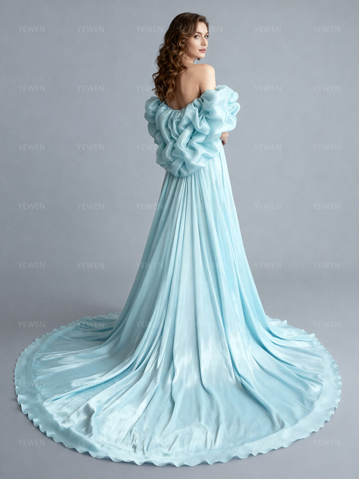Back view of a model wearing an ice blue flower cape bridal accessory with dramatic ruffled layers and a sweeping train.